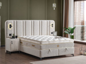 Lit boxspring complet en tissu beige clair avec tete de lit eclairage liseuse et chevets integres ambiance accueillante collection HUGGA Vue décoration